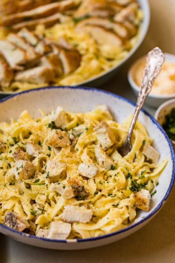 Chicken alfredo in a blue and white bowl with a fork