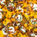 a pan of loaded smashed potatoes covered in cheese and bacon
