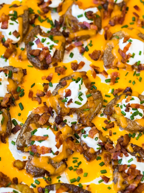 a pan of loaded smashed potatoes covered in cheese and bacon