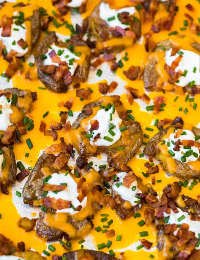 a pan of loaded smashed potatoes covered in cheese and bacon