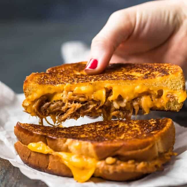 A person holding a delectable pulled pork sandwich.