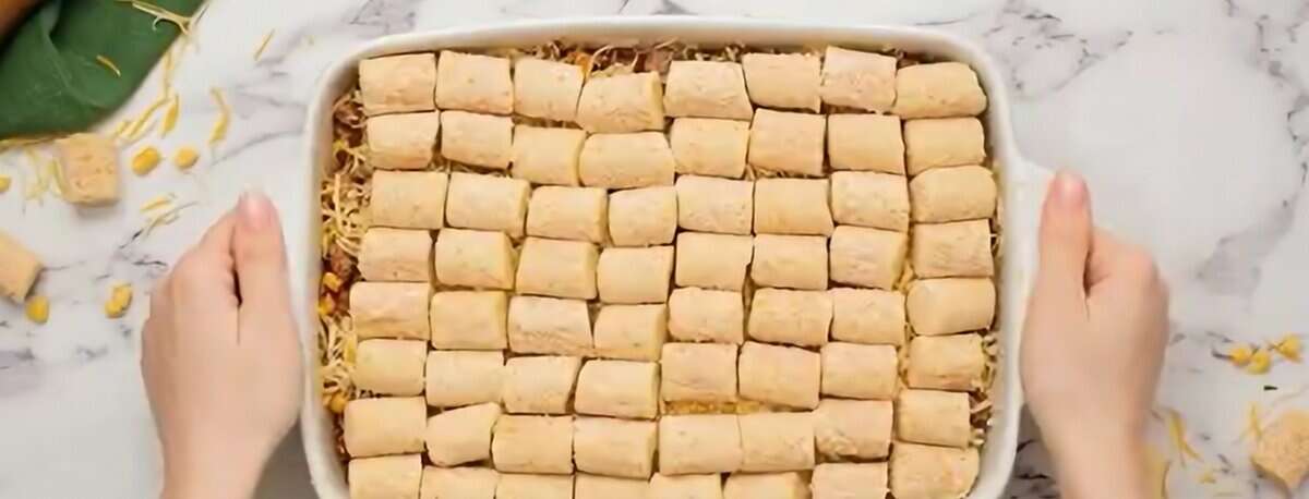 Layered tater tot casserole with tater tots on tops ready for the oven.