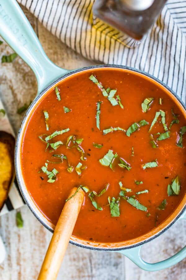 A wooden spoon in the pot of tomato soup