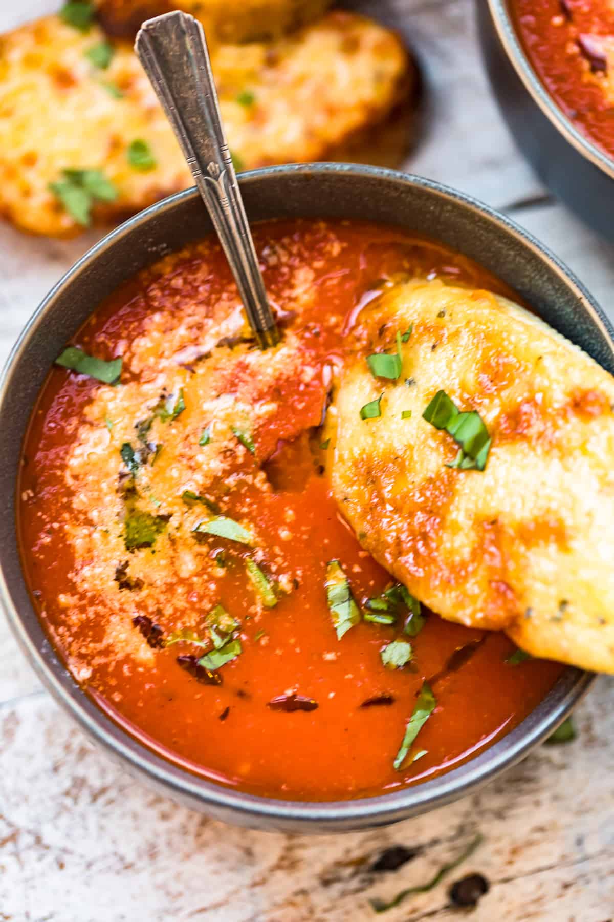 close up on a bowl of tomato soup with a cheese crostini