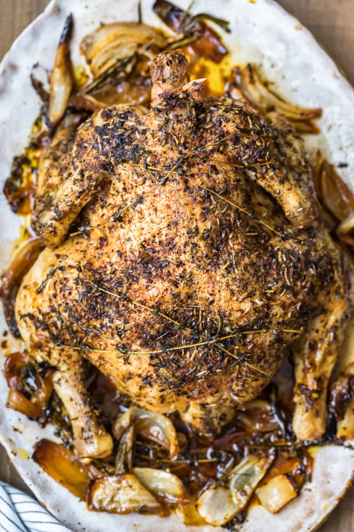 A whole roast chicken with herbs de provence on a white platter