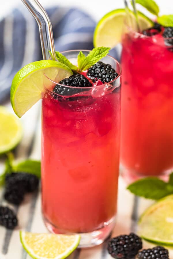 blackberry paloma in glass surrounded by limes and blackberries