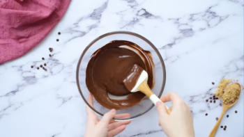 melted chocolate in a glass bowl with a rubber spatula.