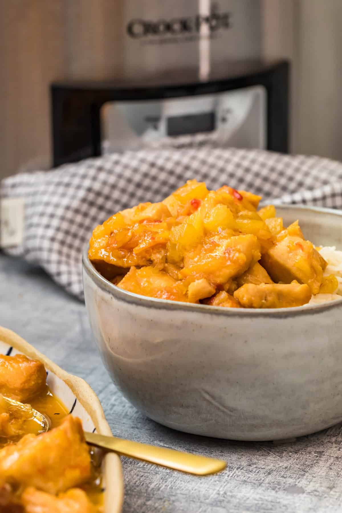 a close up shot of a bowl of sweet and sour chicken in a bowl of rice