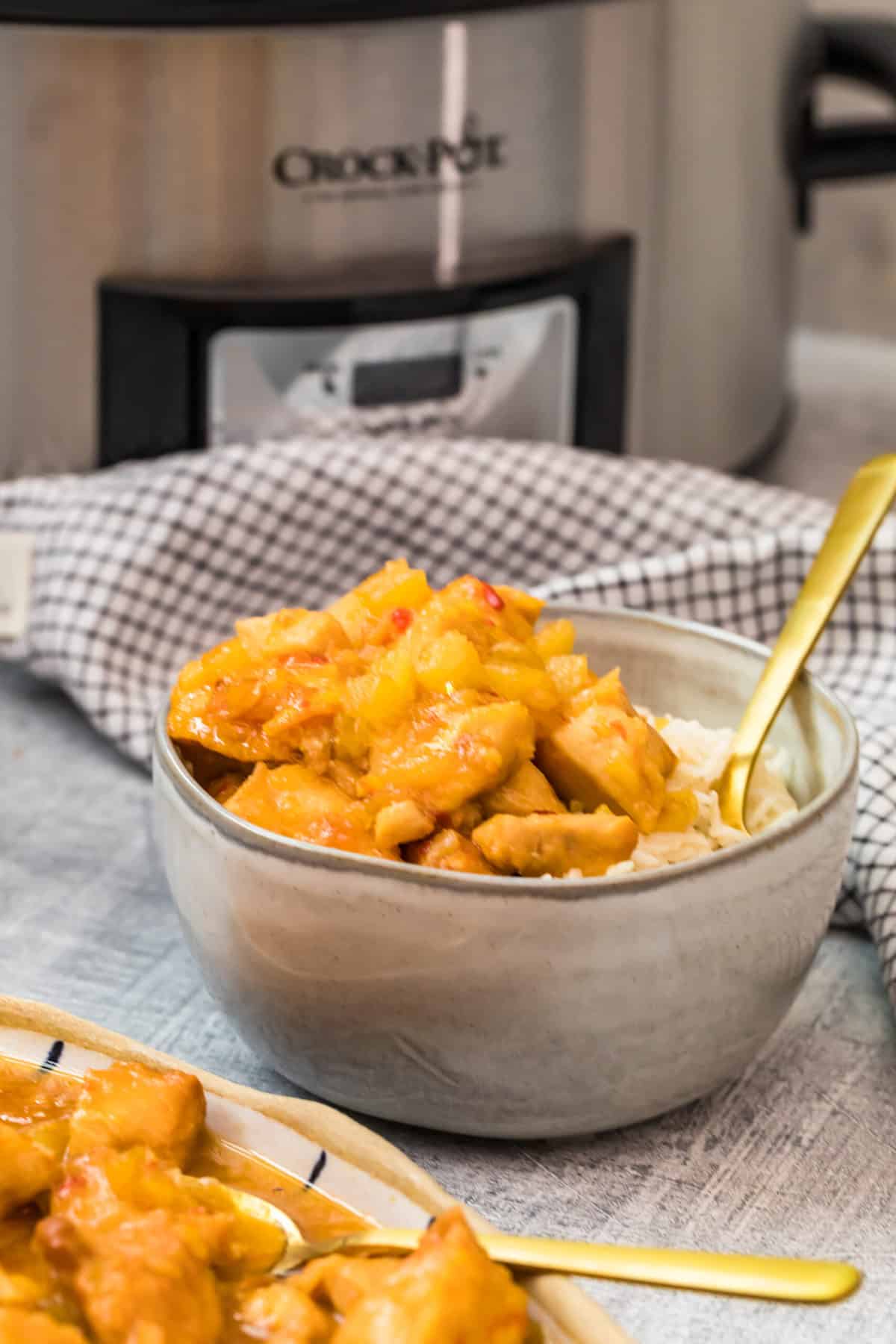 sweet and sour chicken in a bowl with rice in front of a crockpot