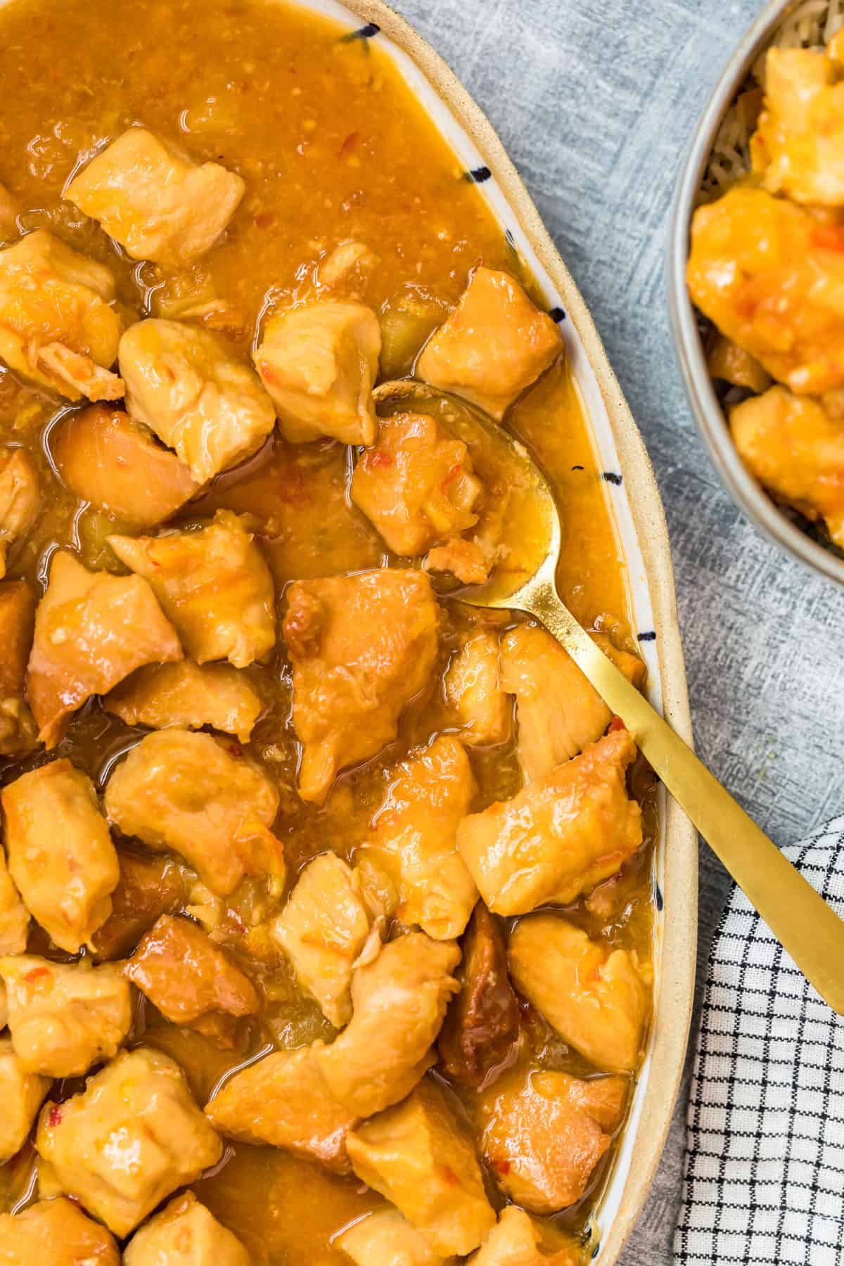 sweet and sour chicken in a serving dish with a gold spoon