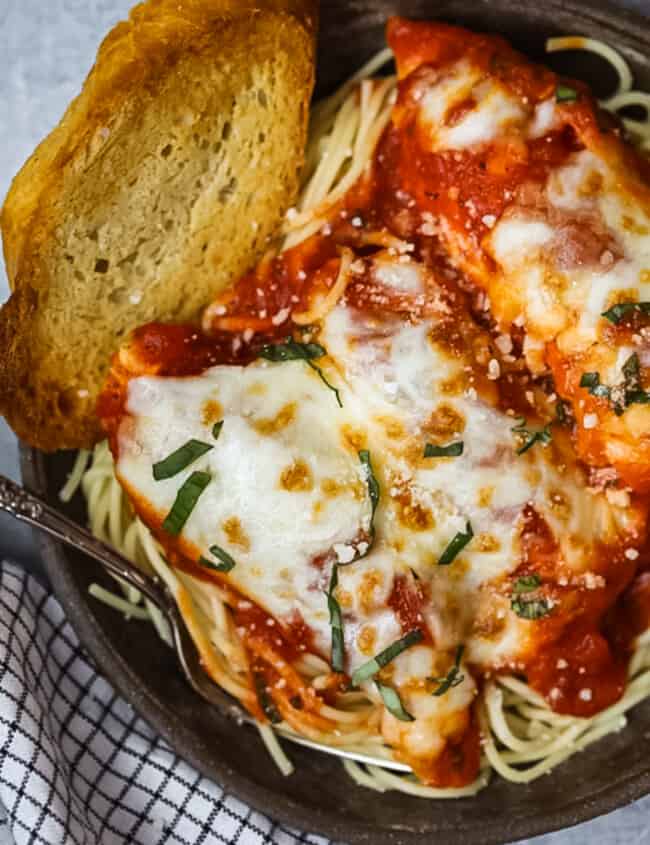 a bowl of chicken parmesan with a slice of bread