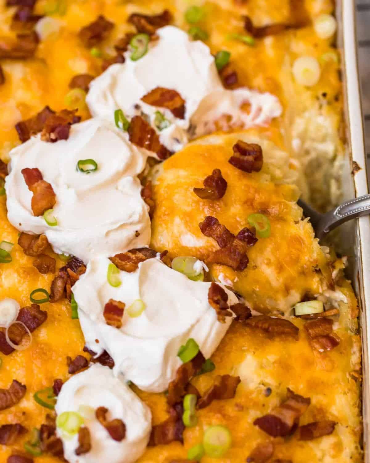 Close-up of loaded hash brown potato casserole with sour cream and bacon on top.  - 3