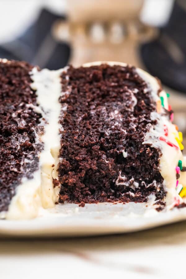 A close up of a piece of chocolate cake on a plate, with piece cut out