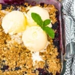 berry crisp in baking dish topped with 3 scoops ice cream