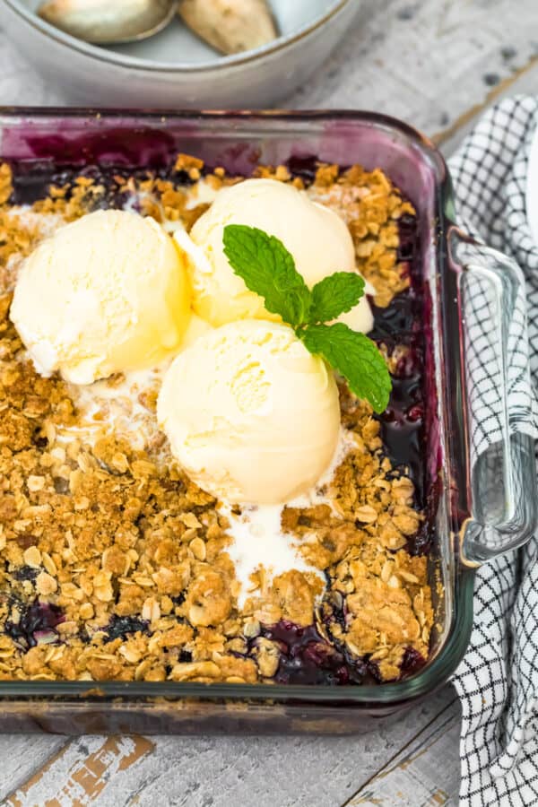 berry crisp in baking dish topped with 3 scoops ice cream