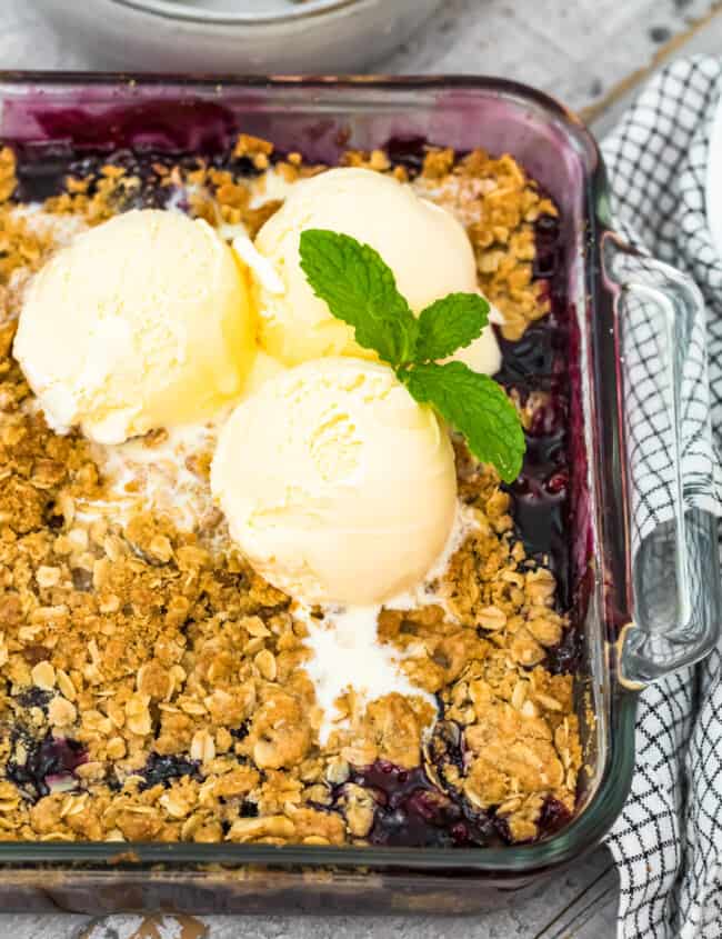 berry crisp in baking dish topped with 3 scoops ice cream