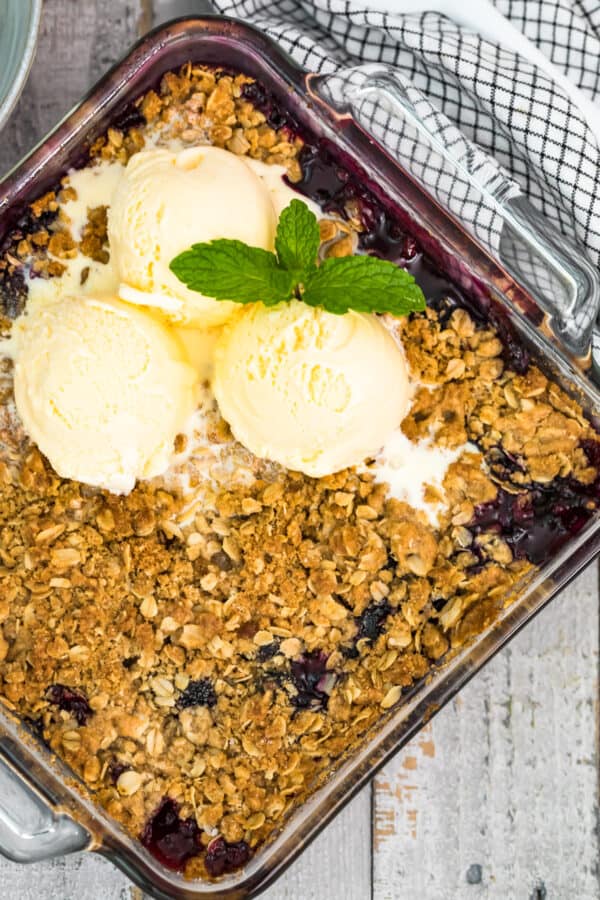 berry crisp in baking dish topped with ice cream