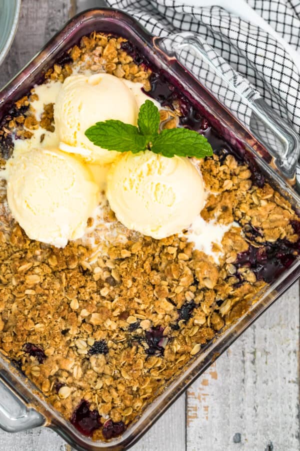 berry crisp in baking dish topped with ice cream