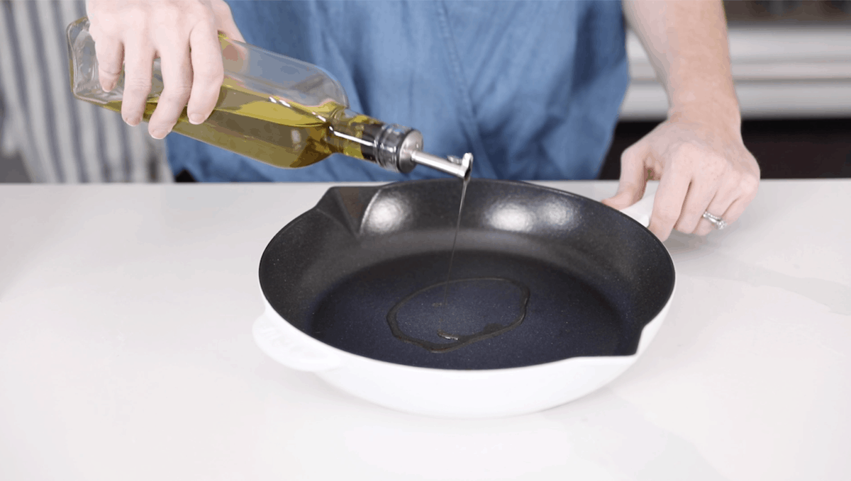 pouring oil onto cast iron skillet