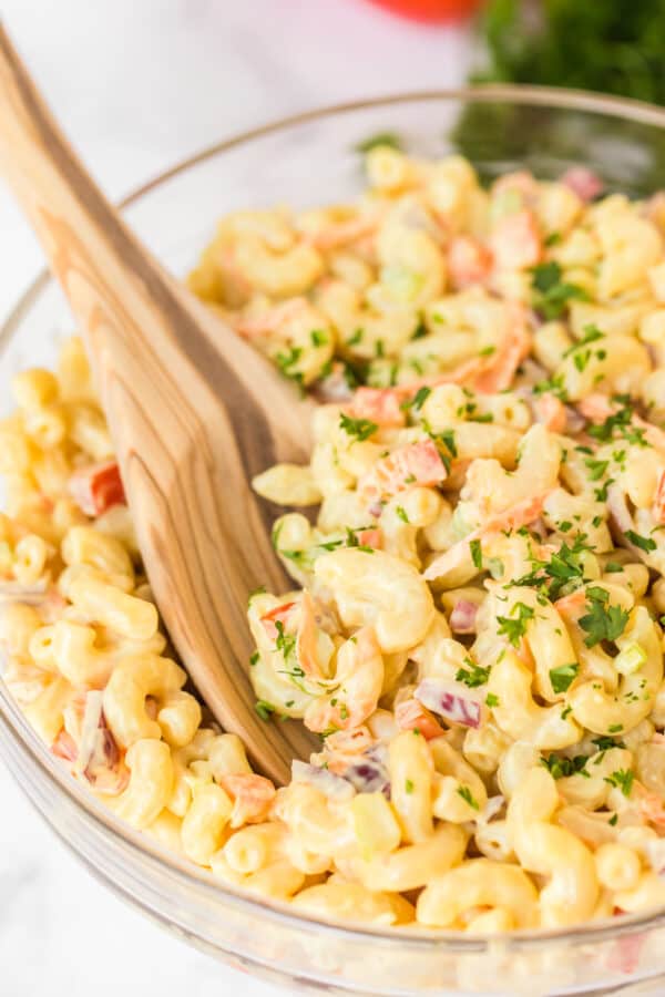 pasta salad in clear bowl with wooden spoon