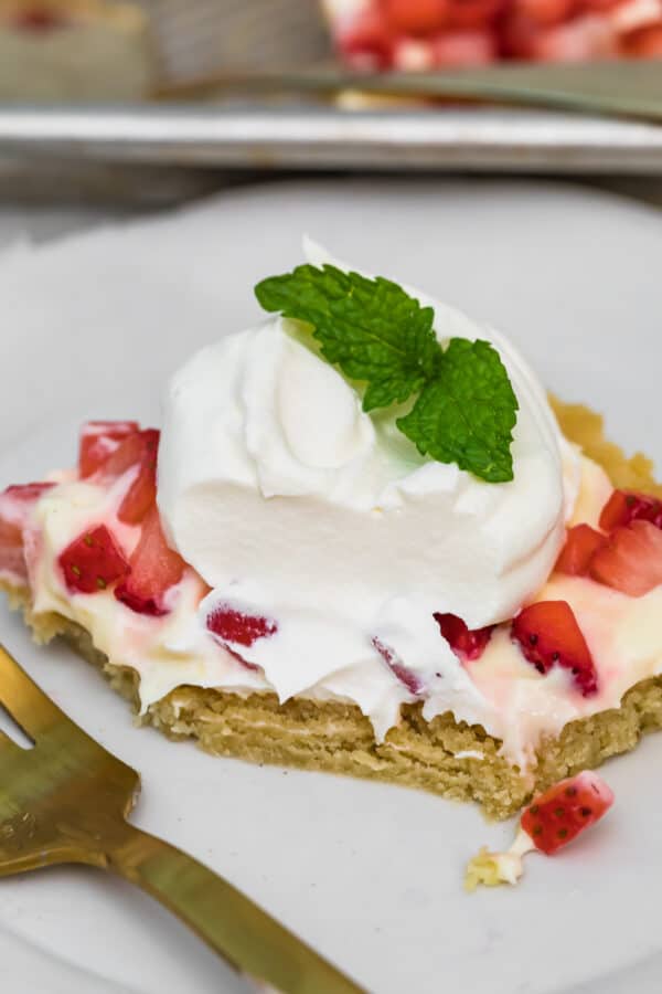 sugar cookie bar topped with strawberries and whipped cream