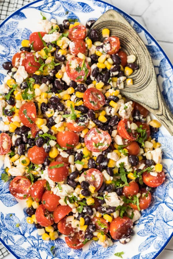 corn salad with tomatoes on blue platter