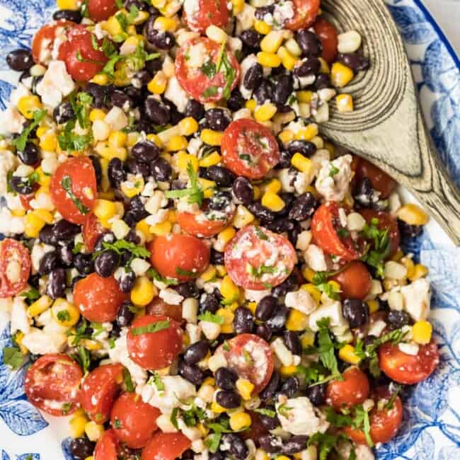 corn salad with tomatoes on blue platter