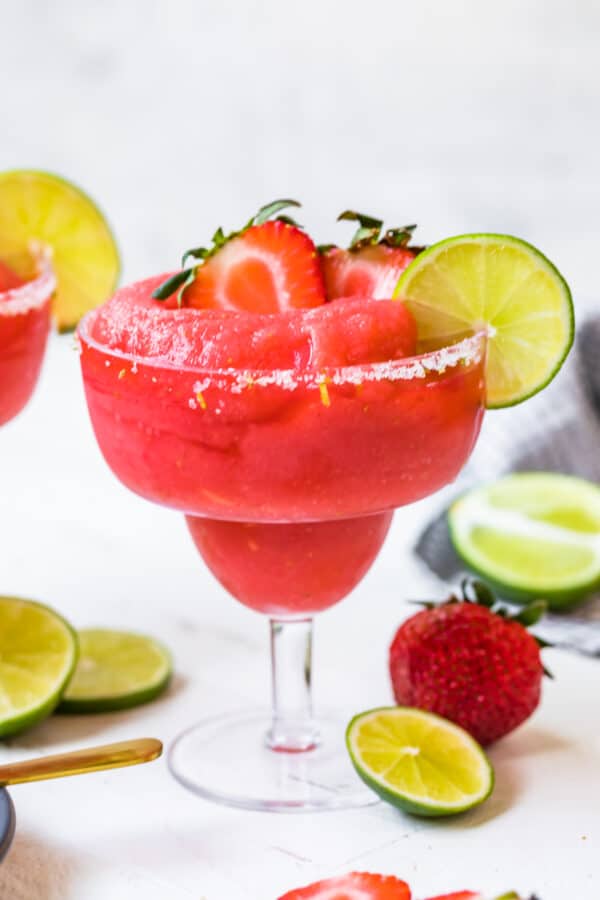 frozen strawberry margaritas garnished with fruit and salt