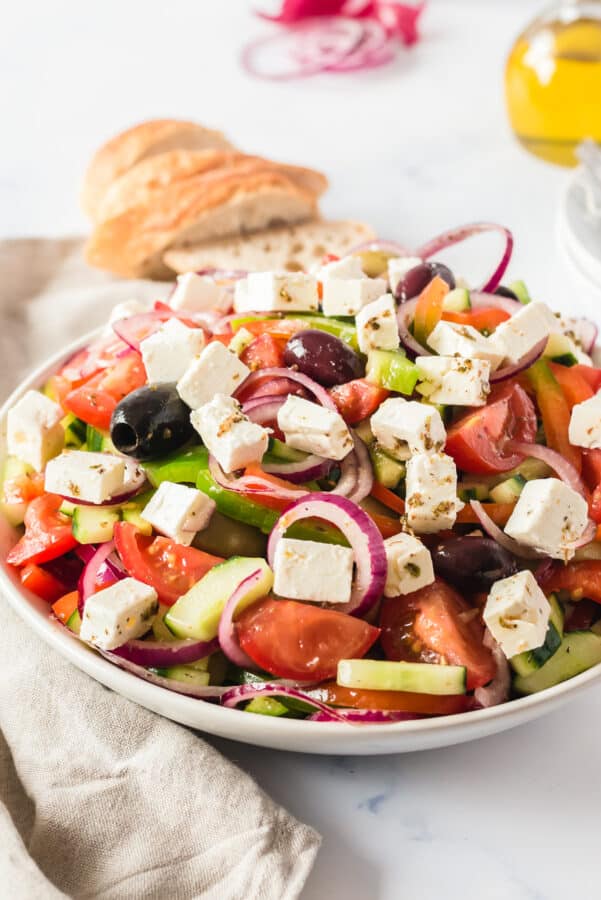 side shot of salad in white bowl with bread