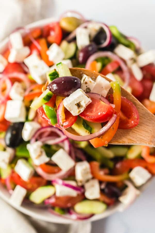spoon lifting up traditional greek salad ingredients