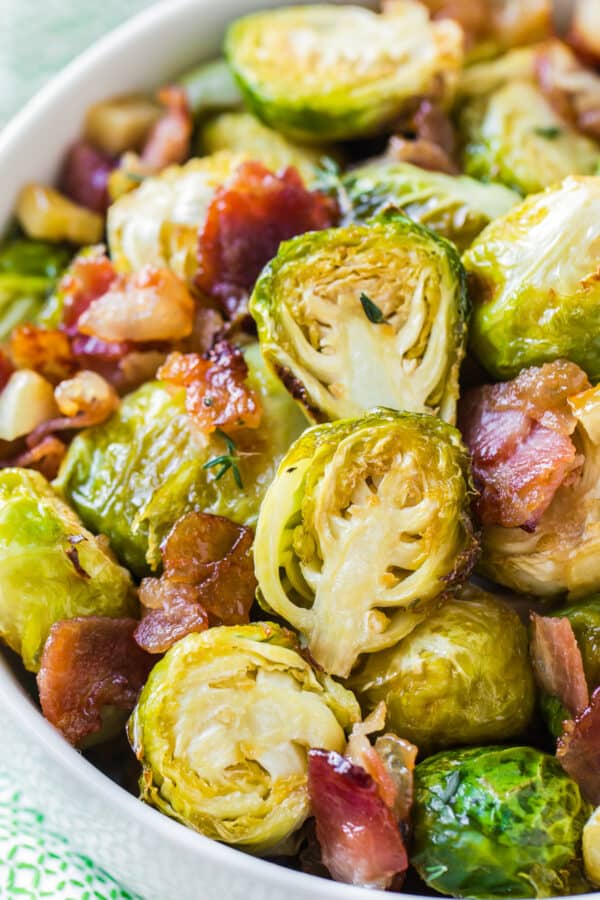 up close image of roasted brussels sprouts in white bowl with bacon