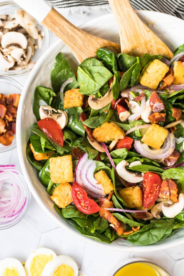 spinach bacon salad with spinach salad dressing in white bowl