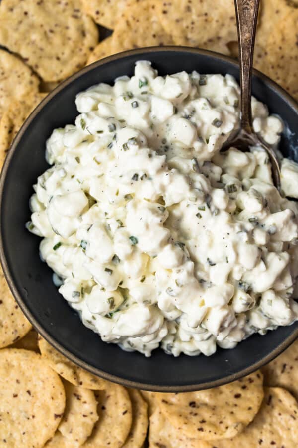 up close image of herbed cottage cheese in bowl surrounded by crackers