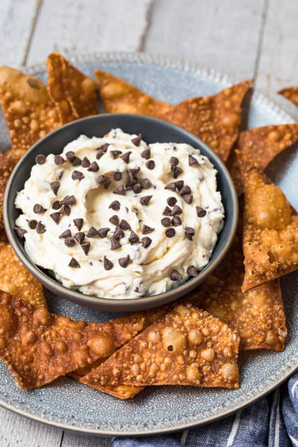 cannoli dip in black bowl surrounded by wonton chips