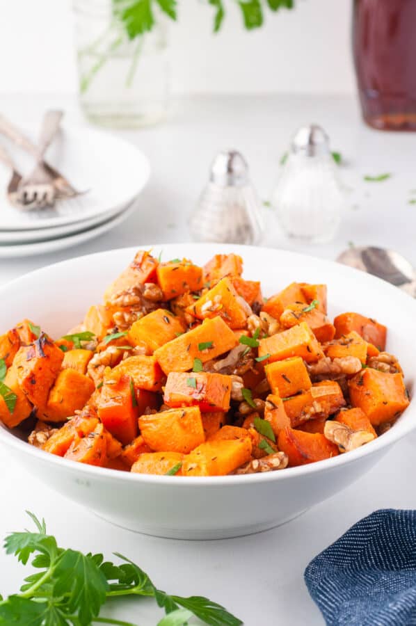 white bowl of roasted sweet potatoes with walnuts