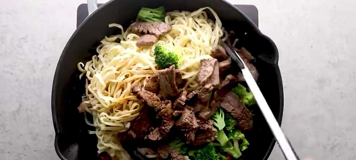 Combining all the ingredients to make Beef Lo Mein.