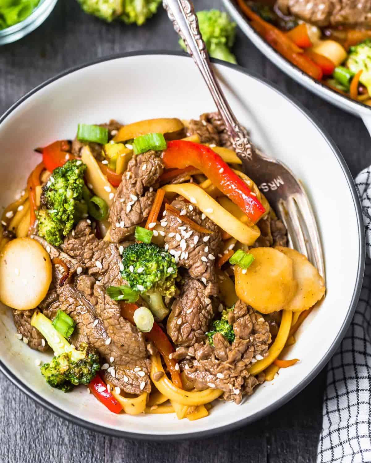 Beef lo mein in a white bowl with a spoon