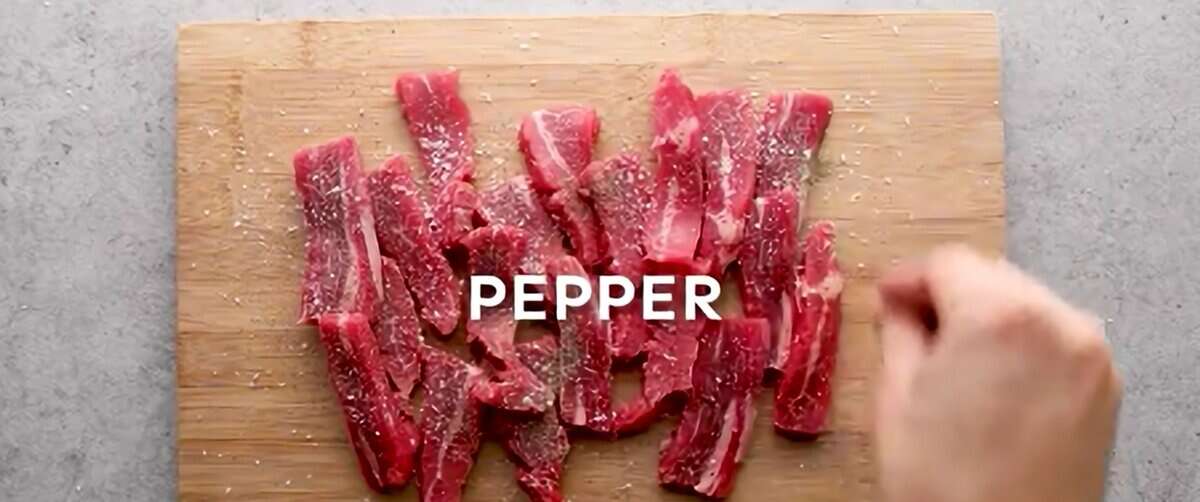 Seasoning beef on a wooden cutting board.