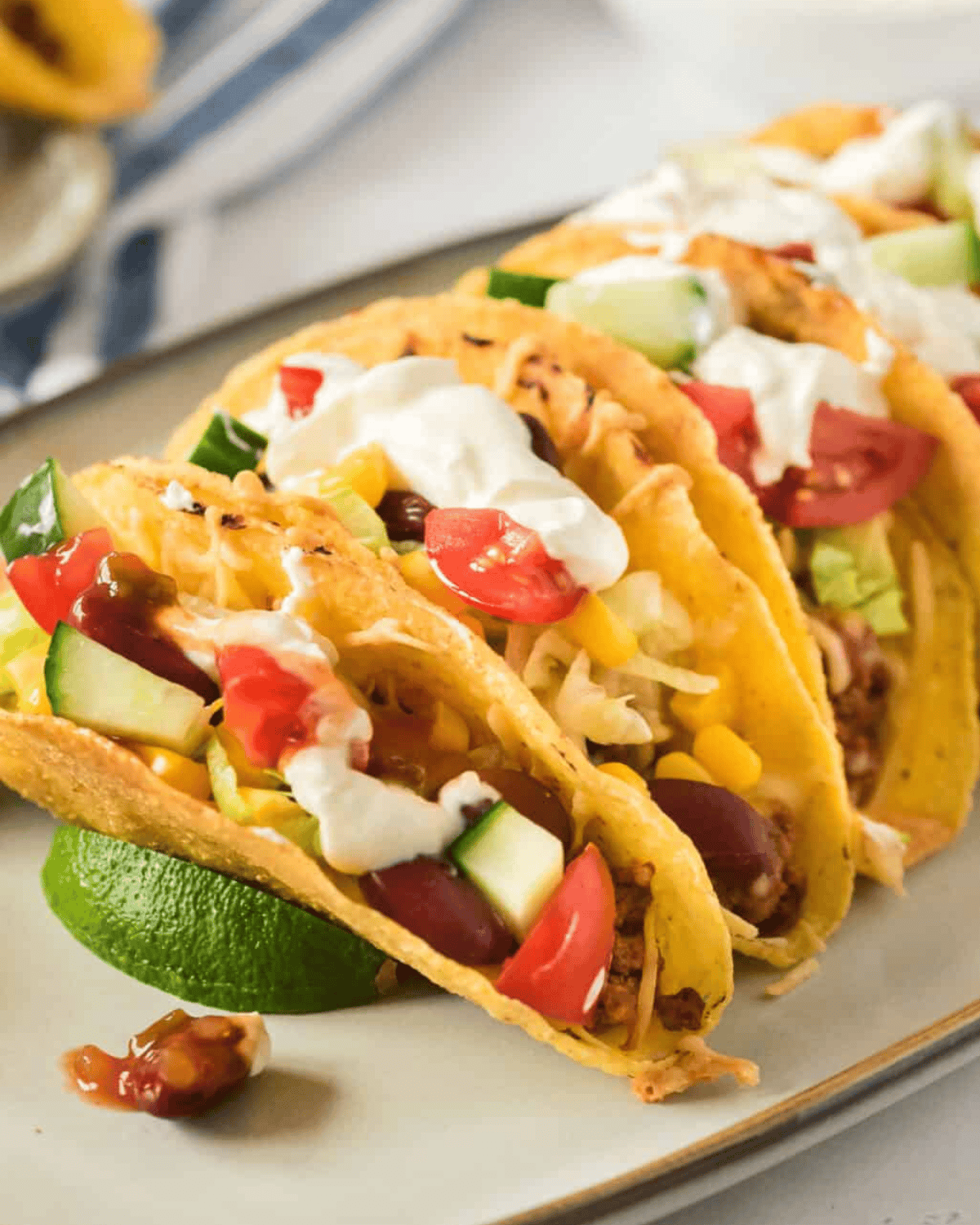 Baked ground beef tacos with toppings on a white plate with a slice of lime.