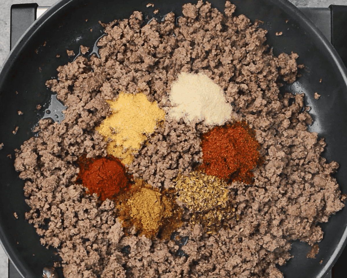Cooked ground beef in a skillet with spices.