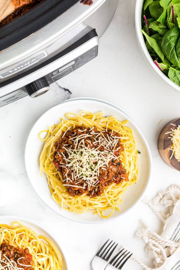 spaghetti sauce over pasta next to crockpot