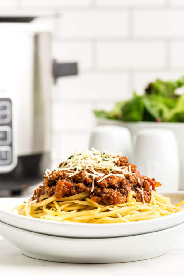 spaghetti sauce over pasta next to crockpot