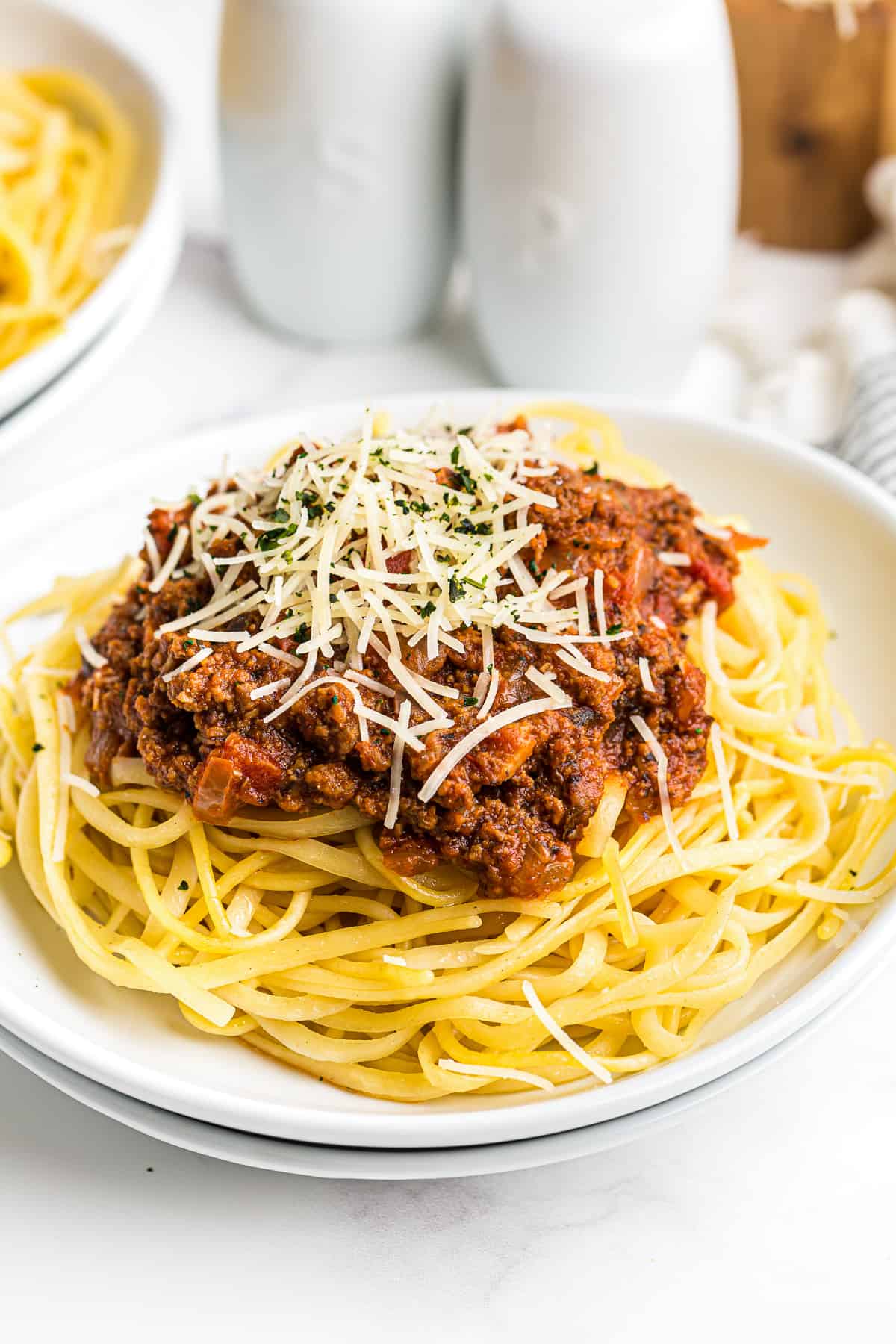 crockpot spaghetti sauce over noodles with cheese on a white plate.