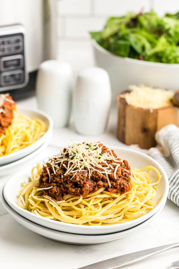 spaghetti sauce over pasta next to crockpot