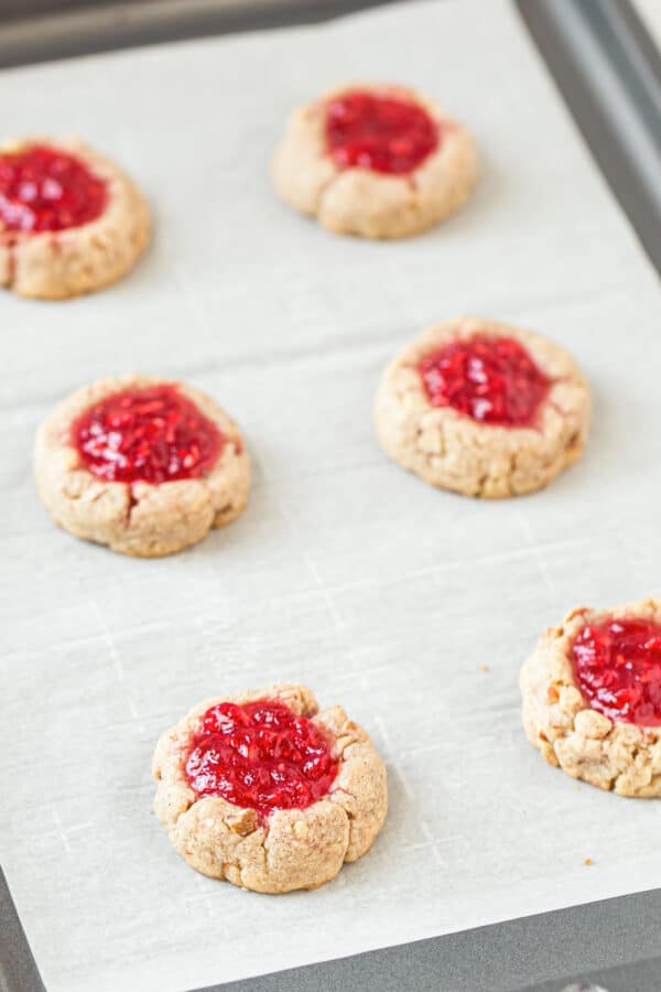 raspberry jam thumbprint cookies on parchment