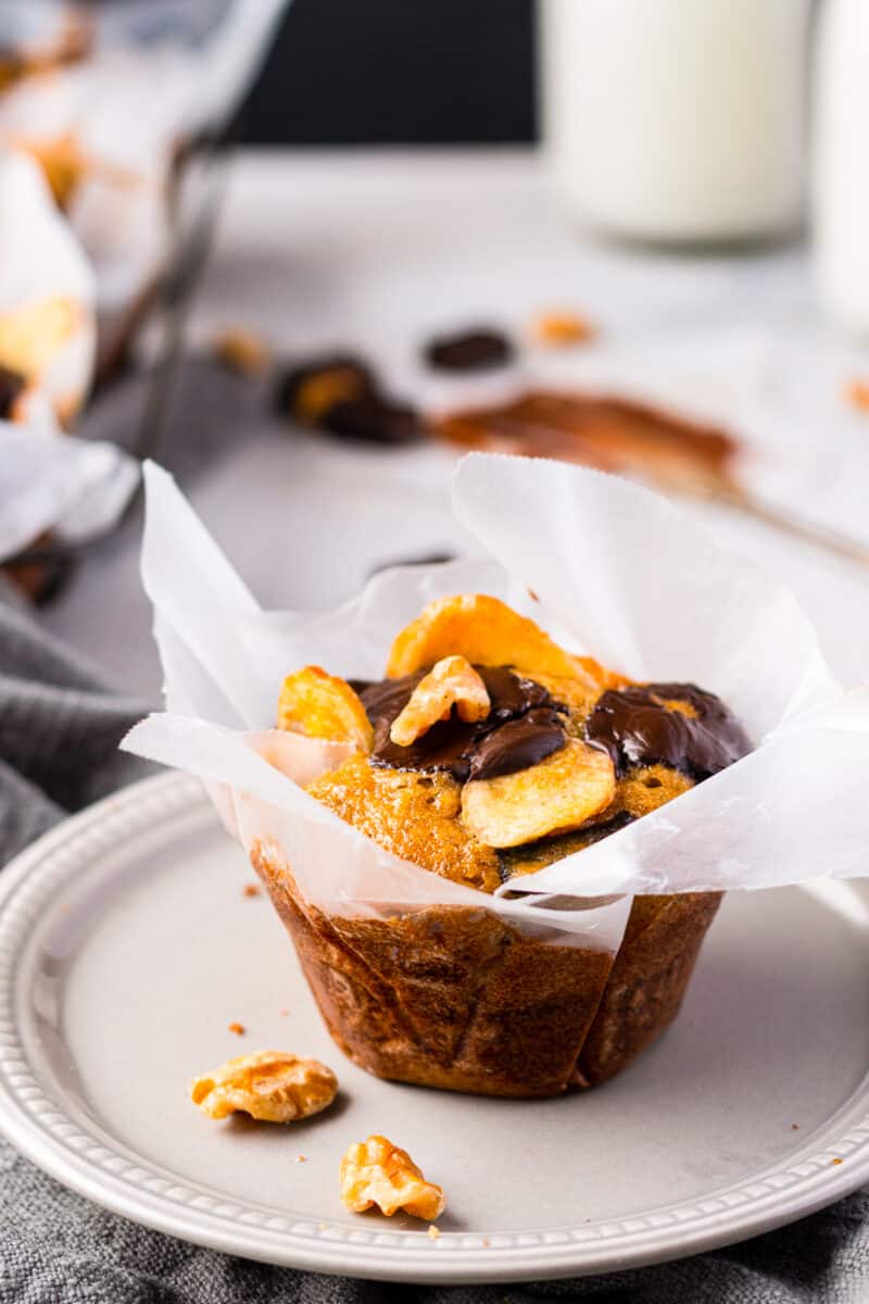 chocolate banana muffin in wrapper on white plate