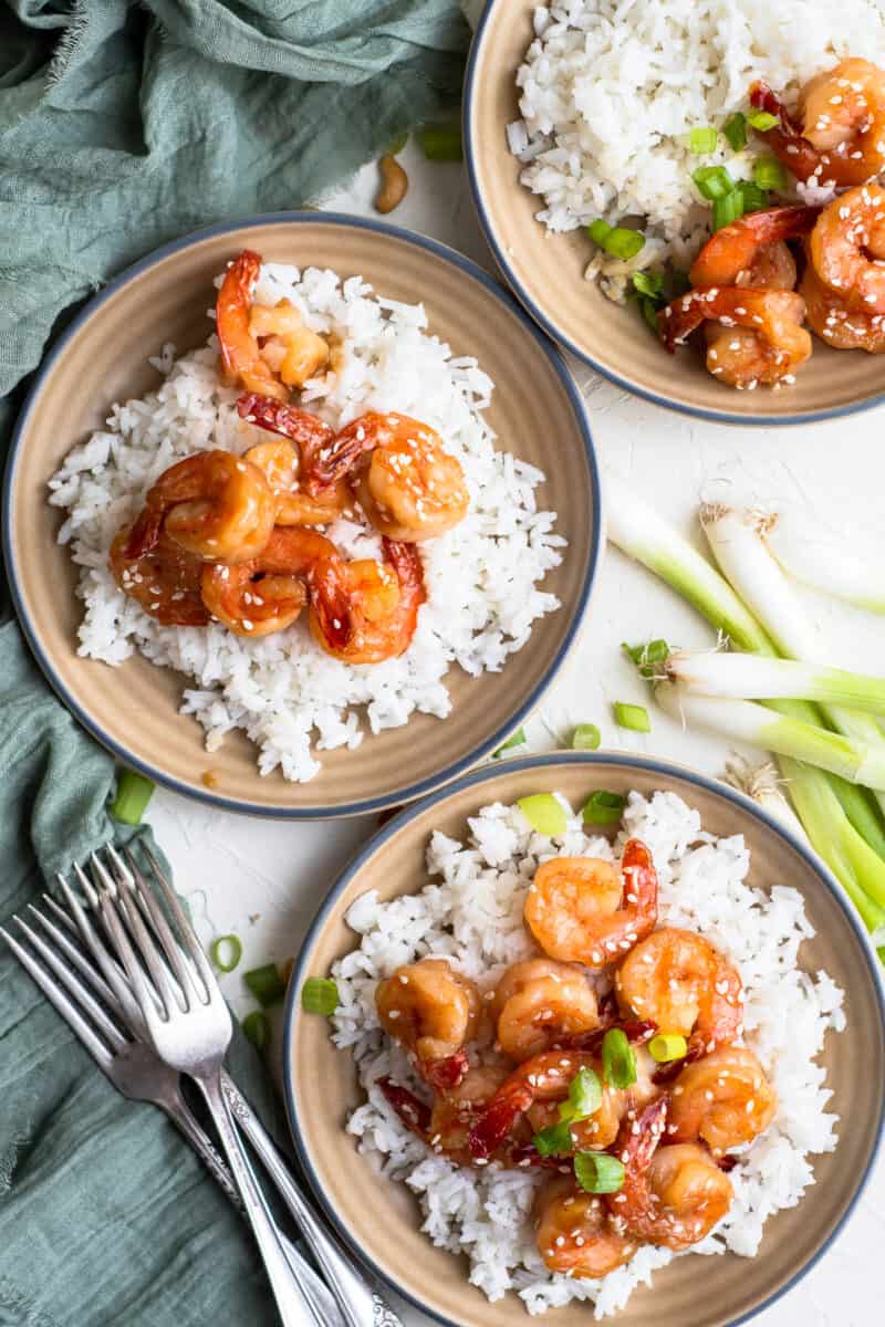 overhead image of three plates with honey sesame shrimp with rice