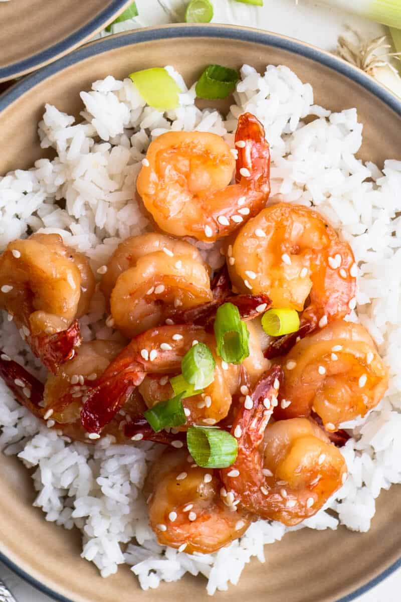 honey sesame shrimp with rice garnished with green onion