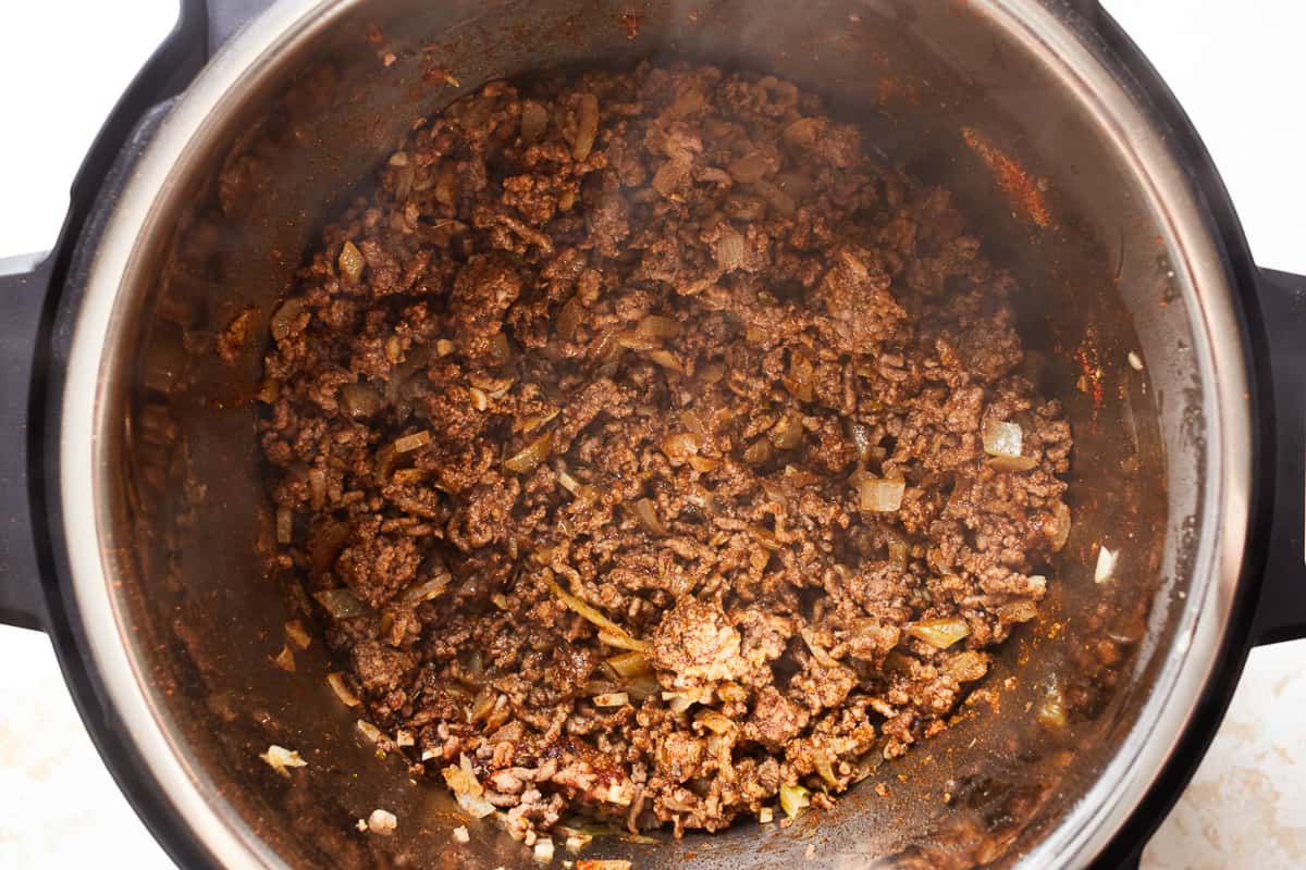 Ground beef with seasonings cooking in an instant pot.