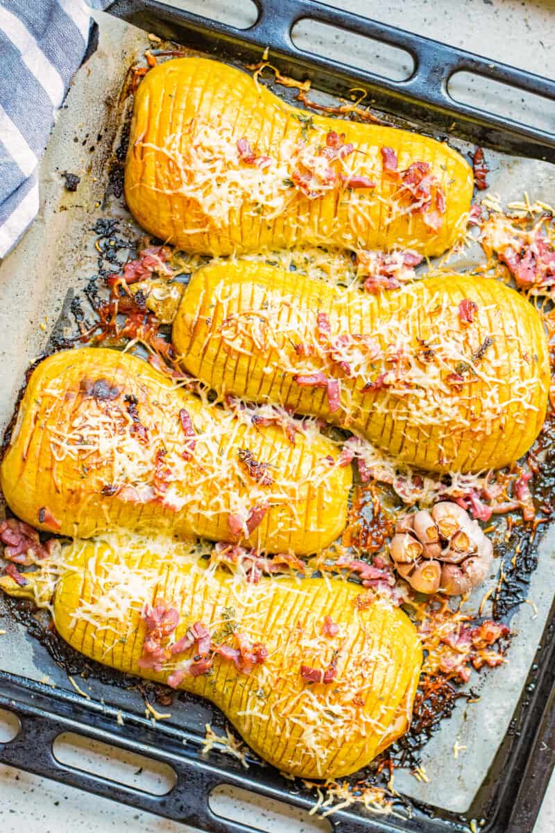 roasted butternut squash hasselback with bacon and cheese on baking sheet.